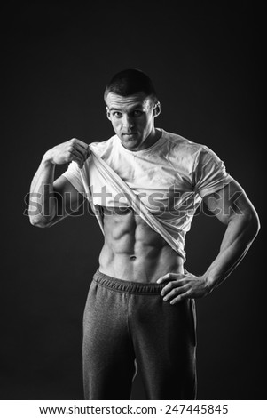Bodybuilder showing his press. A man shows his abdominal muscles, raised his hand t-shirt. Presss, muscles, show, bodybuilding. Sports guy.