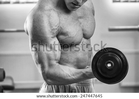 Black and white man in the gym. Working out with weights.Man makes exercises. Sport, power, dumbbells, tension, exercise - the concept of a healthy lifestyle. Article about fitness and sports.