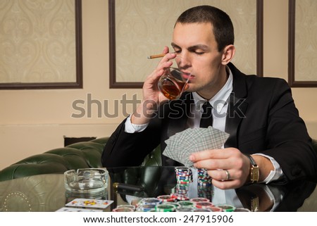 The concept of card games. Man playing poker at the poker table. Playing chip cards and whiskey on the table