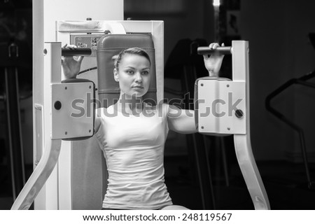 Athletic, pretty blonde trained on the simulator in the gym. Female fitness, strength, youth, beautiful shape - the concept of a healthy lifestyle.