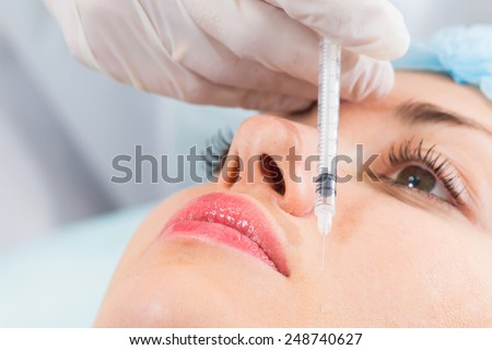 Subcutaneous injection into the girl\'s face. Doctor cosmetologist doing pull-injection in the face model. Syringe, face, needle, lift - the concept of rejuvenation. Tightening of the skin of the face.