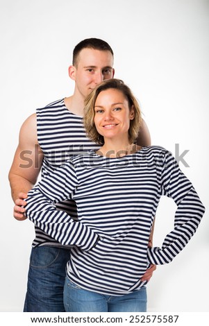 Young couple in love. Athletic man and woman posing on a white background. Muscular strong guy with a beautiful blonde standing arm in arm. Love, husband and wife.