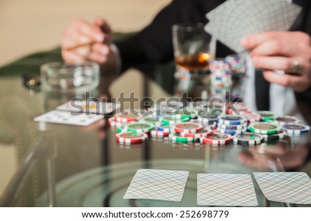Poker player. Young guy in the casino at the gaming table. Man gambling, card games. Cards, chips, whiskey, cigarettes, poker, card game, gambling - gambling concept.