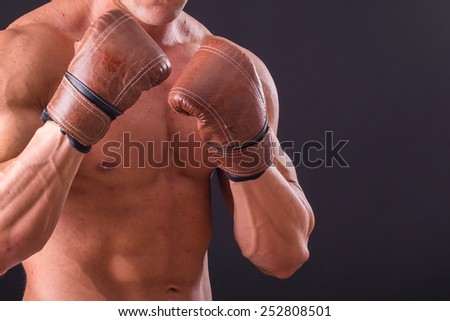 The man in boxing gloves. Young Boxer fighter over black background. Boxing man ready to fight.  Boxing, workout, muscle, strength, power - the concept of strength training and boxing