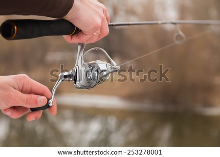 Winter spinning. Fishing in winter. Fisherman on the river bank. Fisherman holding a light spinning rod in his hand. Suburban recreation, sport fishing. Active Life on a fishing trip.