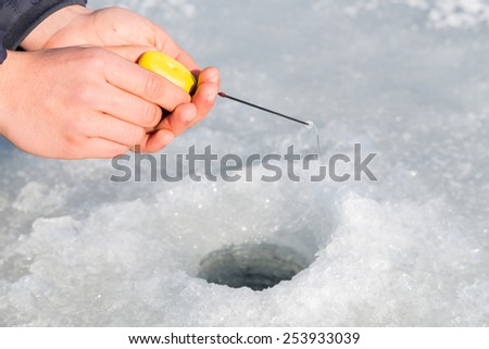 Winter fishing. Ice fishing. Fisherman on ice fishing from the well, a special winter fishing rod. Fishing in winter. Active, cold, fish, winter fishing tackle. Sport winter fishing/