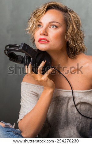 Woman with headphones. Blonde listening to music on stereo headphones. Emotions while listening to music.