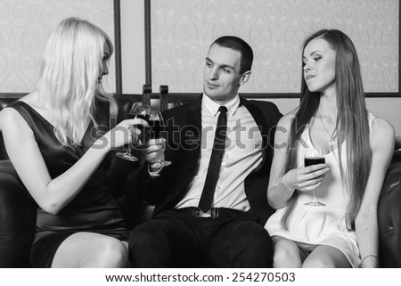 A guy and two girls in the room, tense. Group young people drink wine and enjoy the evening. Human feelings - jealousy, love, passion, betrayal.