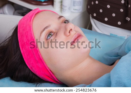 Application of rejuvenating mask on the face of the girl. Cosmetic procedures for the face. Hands beautician applied mask on face of the girl. Facial treatment in a beauty salon.