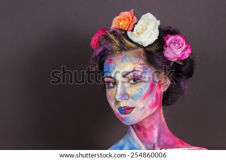 The creative, bright, color makeup. Floral makeup. Art makeup. Tone, powder, make-up. Multi-colored roses in her hair girl. Creative floral makeup on the model, background floral pattern.