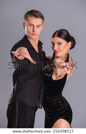 Ballroom dancers dancing. Dancers on a gray background. Man and woman dancing. Man and woman posing in dance position.