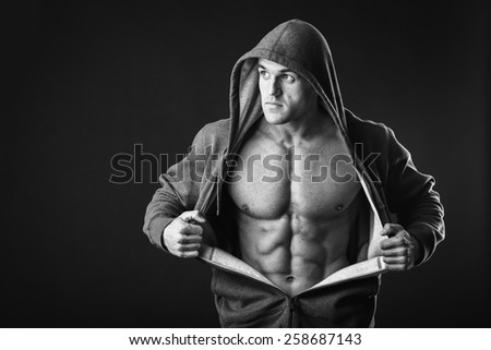 Sports guy in a tracksuit. A man in a sports jacket with a hood. The guy takes off her jacket and shows his muscular body. Fitness, strength, courage, a trained man.