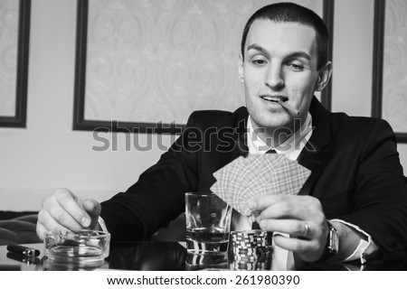 Poker player in the casino with glass of whiskey and cards at the gaming table.