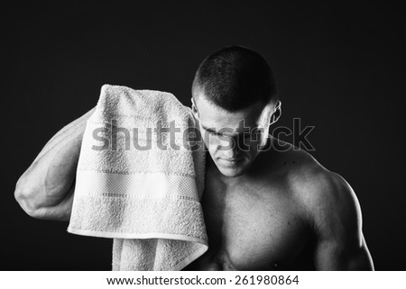 Healthy muscular young man after a workout on dark background.Fitness man holding a orange  towel against dark background.Strong Athletic Man Fitness Model Torso showing  abs. holding towel.