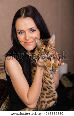 Beautiful woman with cat portrait. Brunette with bengal cat close-up.
