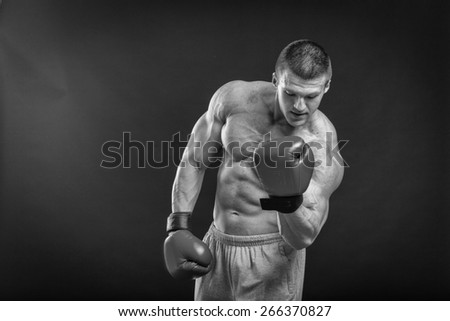 The man in boxing gloves. Young Boxer fighter over black background. Boxing man ready to fight.  Boxing, workout, muscle, strength, power - the concept of strength training and boxing
