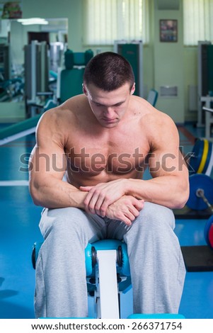 A man pumping abdominal muscles. Man in the gym. Man makes exercises. Sport, power, dumbbells, tension, exercise - the concept of a healthy lifestyle. Article about fitness and sports.