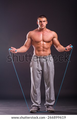 A strong man with a rope. Muscular bodybuilder posing on a black background, shows his muscles.