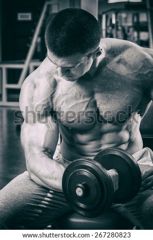 The process of physical exercise with dumbbells. The man is engaged in the gym. Training in the gym. Healthy lifestyle. Photo in creative.