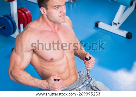 Chic sporty man doing exercises on the simulator in the gym. Sport, strength, youth.