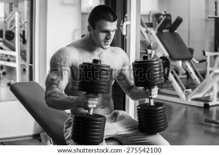 Strength training with dumbbells. Husky holds a large dumbbell in hand. Sport, bodybuilding, healthy lifestyle.
