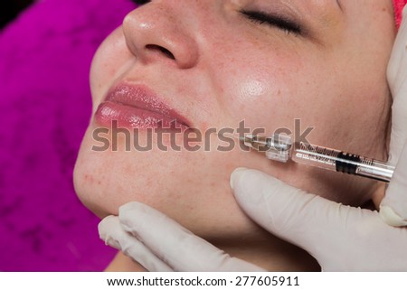 Beauty injections. Beautician makes the injection of anti-aging products in the face of the girl.