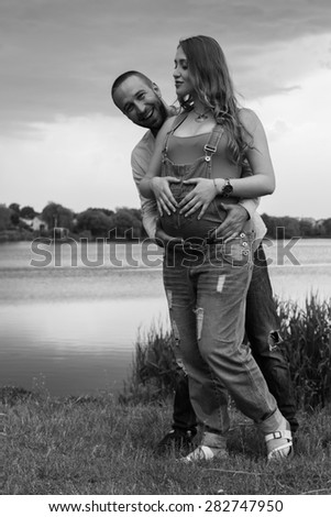 Pregnancy, family, expectation of the child. Young couple on the lake shore, the girl pregnant. Subject warm family relationships, family.