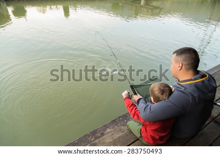 Dad and son go fishing on the lake.