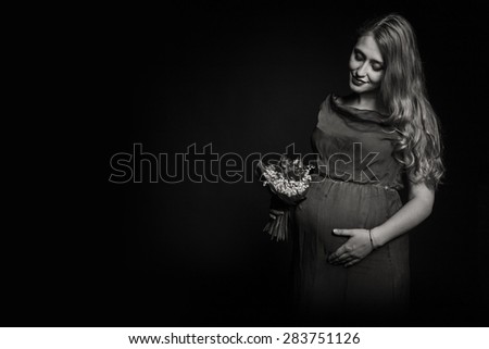Subject pregnancy, waiting child. The ninth month of pregnancy. Pregnant girl with flowers. Photography in low key, sepia.