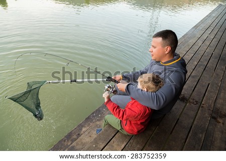 Father and son in the process of catching fish on the lake. Fish on the hook. Happy childhood child. Loving father. Family fishing.