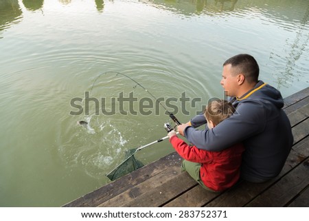 Father and son in the process of catching fish on the lake. Fish on the hook. Happy childhood child. Loving father. Family fishing.