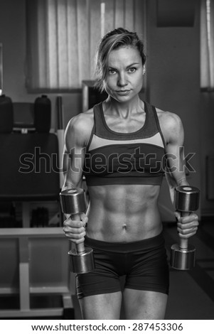 Gym woman push-up strength pushup exercise with dumbbell in a fitness workout. Athletic young woman doing exercises.