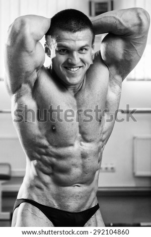 Handsome and strong man with beautiful body doing exercises in gym