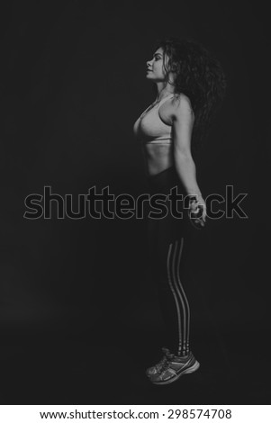 Beautiful, athletic girl with a skipping rope on a black background. Sports / training, women\'s fitness.