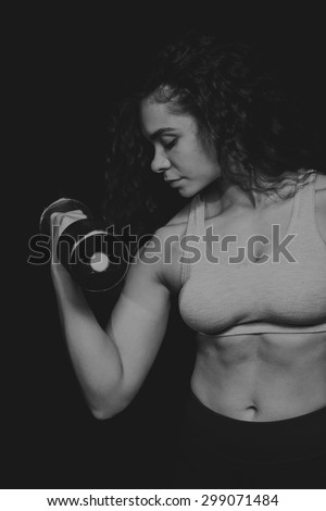 Strong, curly brunette with dumbbells. Female fitness, sport, bodybuilding.