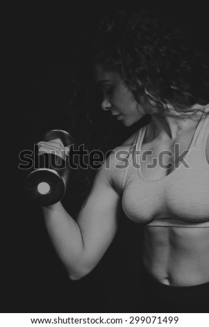 Strong, curly brunette with dumbbells. Female fitness, sport, bodybuilding.