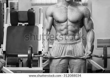 Athlete demonstrates muscles in the gym. Muscle tension of exercise performed. Weight training. Bench weights and work with dumbbells.
