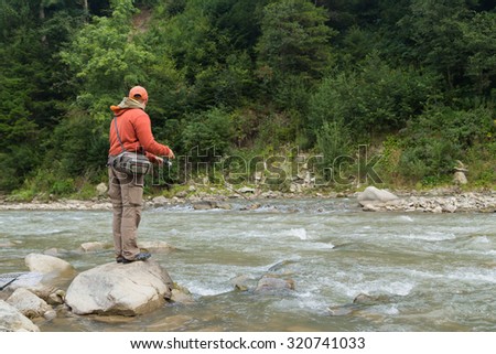 Fishing. Fishing in the highlands. Fisherman on the shore of a mountain, fast river. Trout fishing on the river. Active holiday in the mountains.