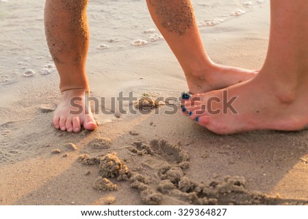 Foot on sea sand. Women\'s and children\'s feet in the sand. Beautiful pedicure. Photo for fashion, travel, social magazines and websites. A beautiful photo for background.