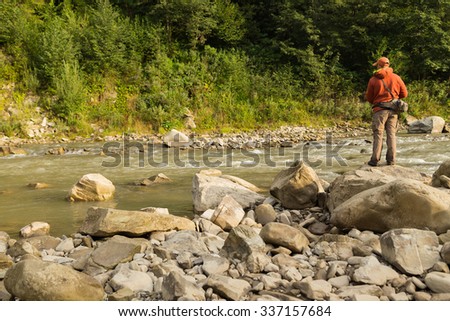 Fisherman on a mountain river catch exotic fish. Trout fishing in the Carpathian rivers. Untouched nature of the mountains. Photo for fishing and Natural magazines, posters and websites.