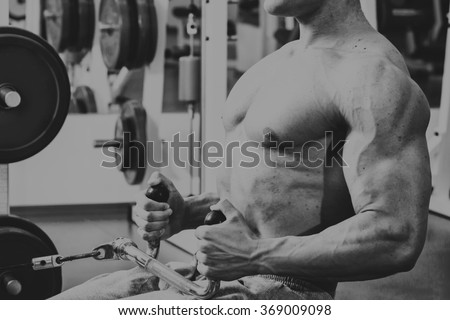 Muscular man in the gym. Work on the arm muscles. Training on a simulator. Exhausting work on his body.