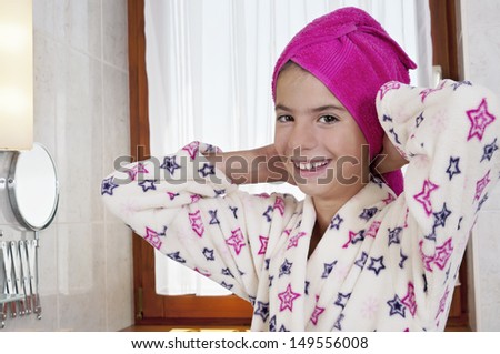 Young woman in bath robe and towel on head in bright bathroom
