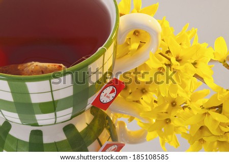 Large mug with tea and yellow backlit, reflection and flower