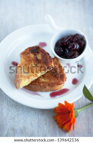 pieces of toasted bread on the plate, cherry jam and orange flower