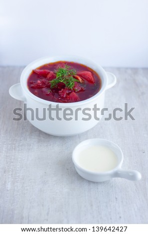 red  borsch in the white plate and sour cream in the gravy boat