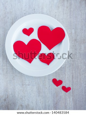 Big and small hearts on the white round plate, top view