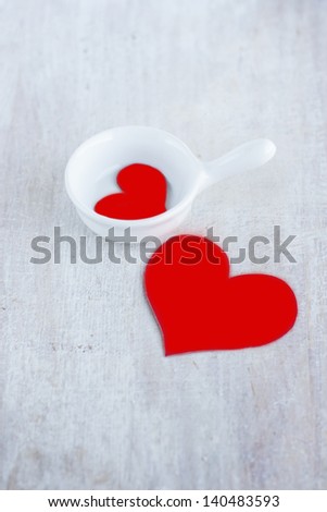 Two red hearts in the white gravy boat and on the board