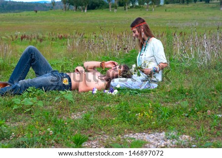 young hippie couple, men lie, women twine a wreath with flowers