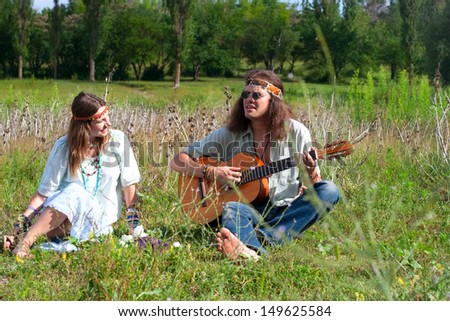 young hippie men play on the guitar and sing, young hippie woman