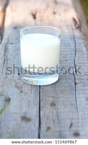 fresh cow\'s milk in the transparent glass on the old wood board